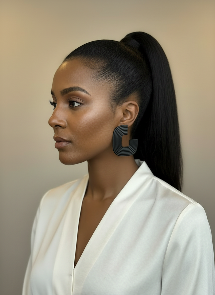 A model styled wearing a white blouse and a pair of black 'Gia' statement earrings, handmade by Sunni Dineen, against a beige background.