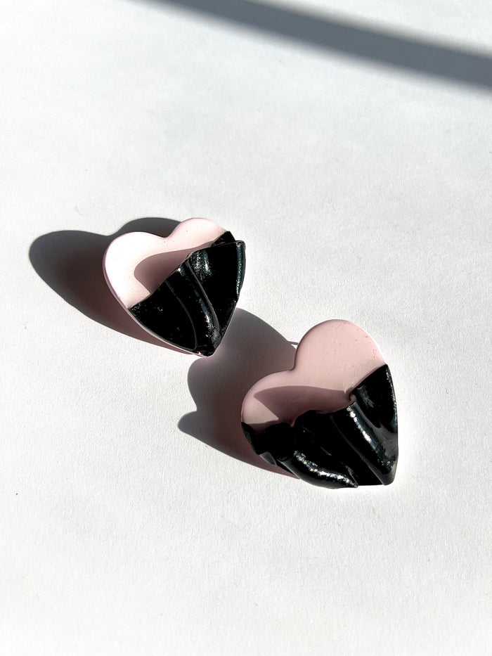 The Draped Heart Statement Earrings in pink-black displayed on a white surface, handmade by Sunni Dineen.