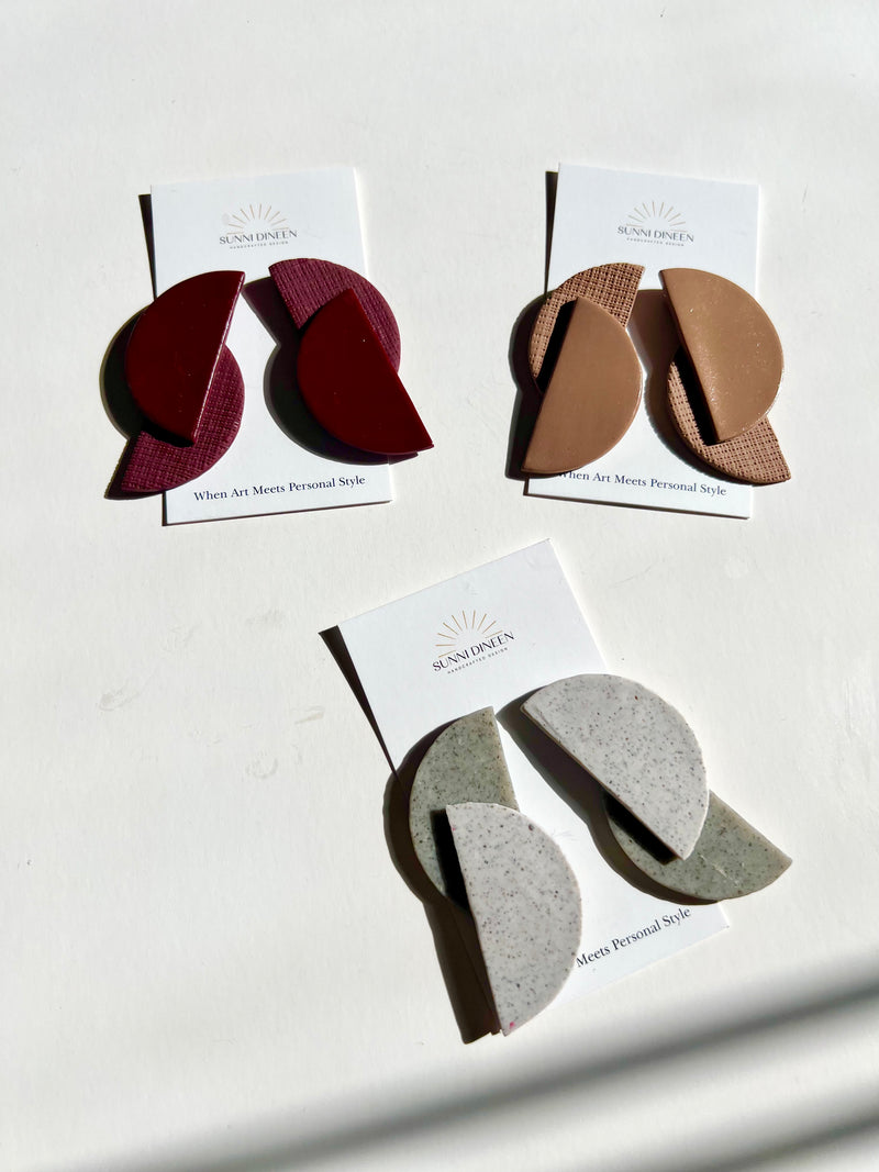 Three pairs of Elodi geometric statement earrings shown in three different color choices on a white surface handmade by Sunni Dineen.