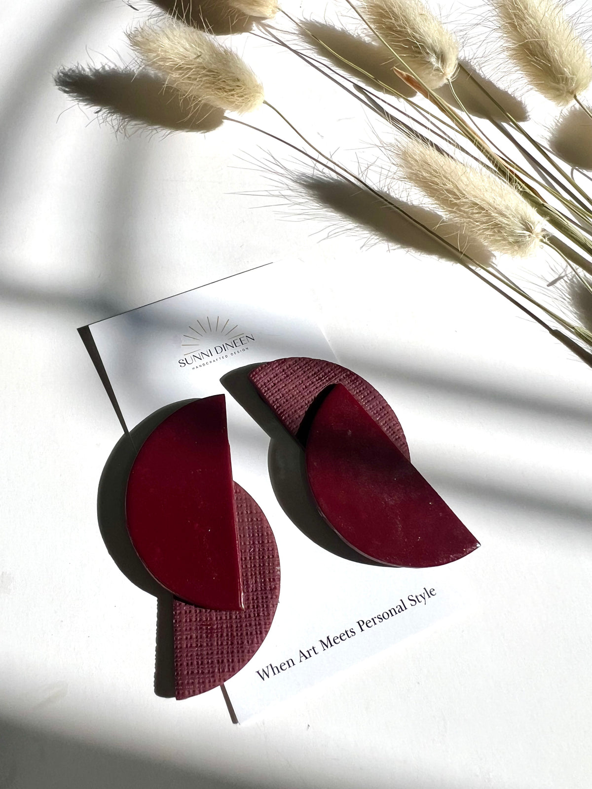 Elodi geometric statement earrings in bordeaux on product card with Sunni Dineen Handcrafted Design logo — handcrafted jewelry for women.