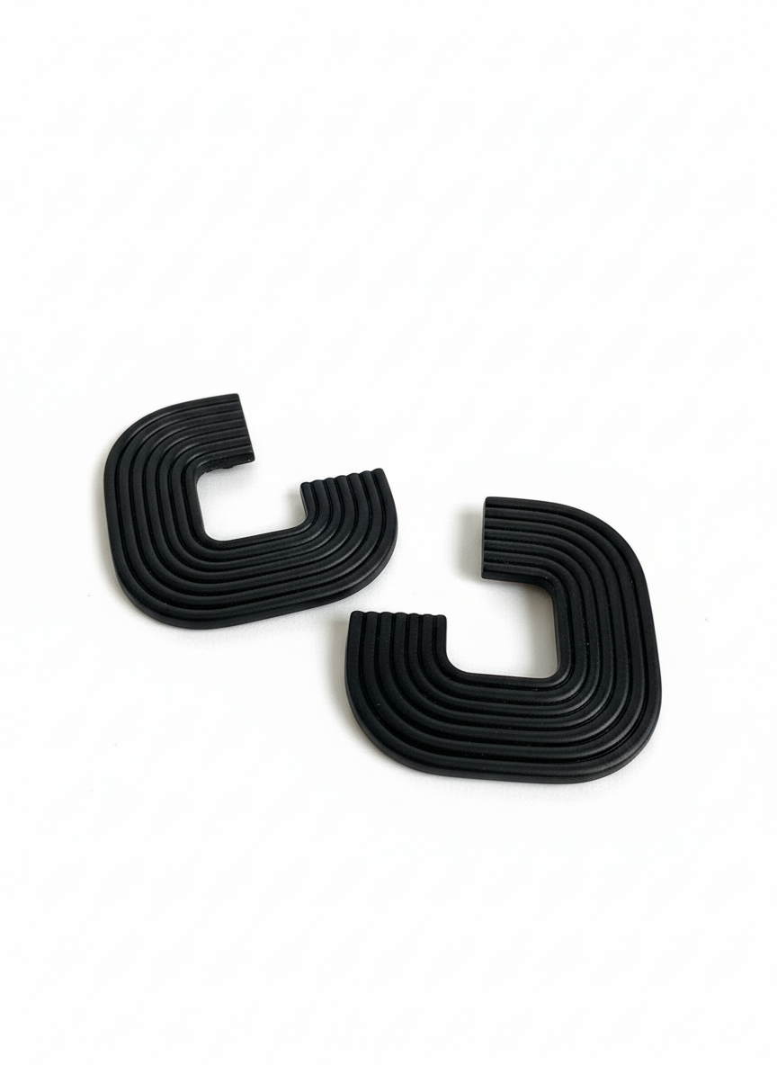 A pair of black 'Gia' statement earrings on a white surface, handmade by Sunni Dineen.