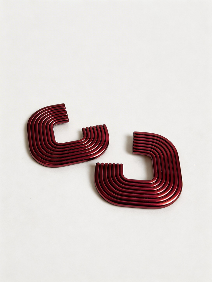 A pair of metallic cranberry 'Gia' statement earrings on a white surface, handmade by Sunni Dineen.