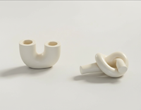An ivory U-shaped candlestick holder & ivory knot candlestick holder handmade by Sunni Dineen, displayed on a white surface.