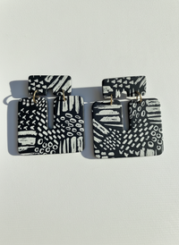 Pair of black and white patterned 'Kalani' statement earrings, handmade by Sunni Dineen, on a white textured surface.