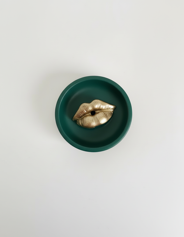 A green Sculptural Lips Incense Holder with gold lips, handmade by Sunni Dineen, displayed on a white surface.