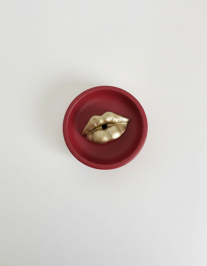 A red Sculptural Lips Incense Holder with gold lips, handmade by Sunni Dineen, displayed on a white surface.