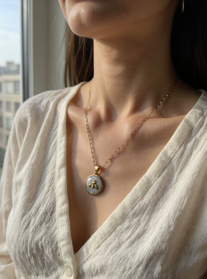 Gold Queen Honeybee Pendant Necklace in Silver-Bell color variant worn by a woman in a light-colored top, with a blurred background.