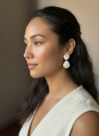 Model wearing a cream linen vest and apair of gold leaf seashell bauble earrings handmade by Sunni Dineen.