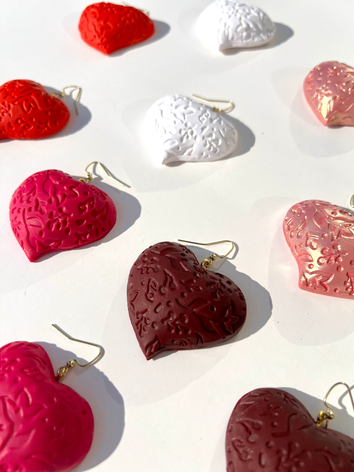 The Puffy Heart Statement Earrings in all colors displayed on a white surface, handmade by Sunni Dineen.