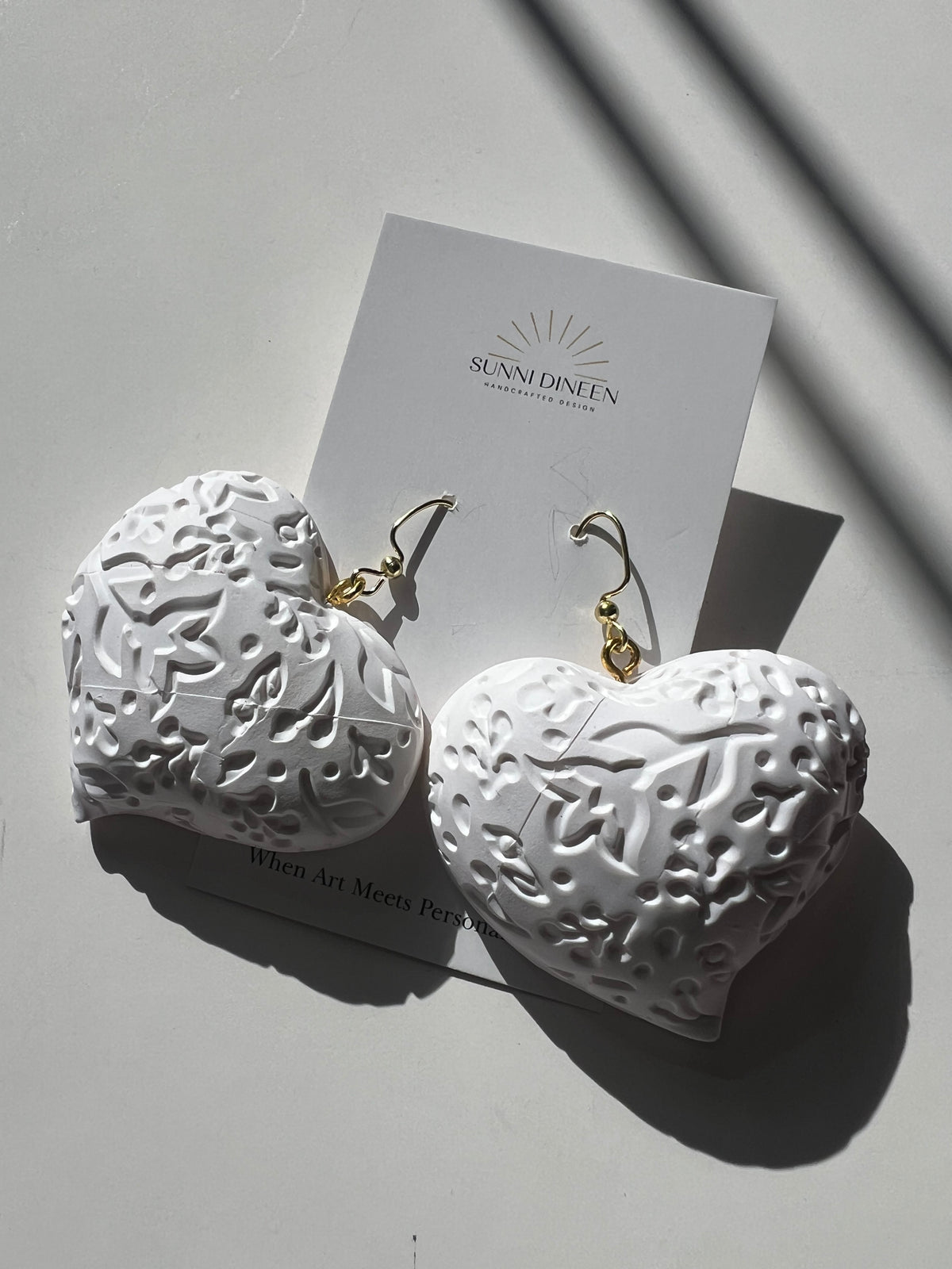 The Puffy Heart Statement Earrings in white, displayed on a white earring card on a white surface, handmade by Sunni Dineen.