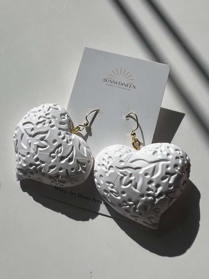 The Puffy Heart Statement Earrings in white, displayed on a white earring card on a white surface, handmade by Sunni Dineen.