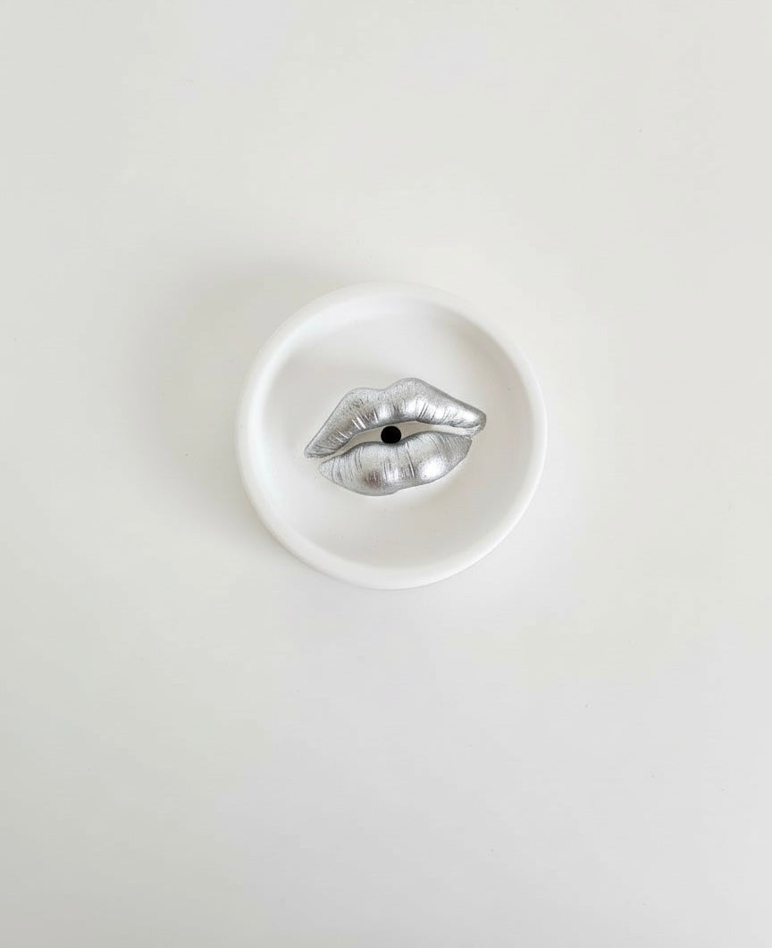 An ivory Sculptural Lips Incense Holder with silver lips, handmade by Sunni Dineen, displayed on a white surface.