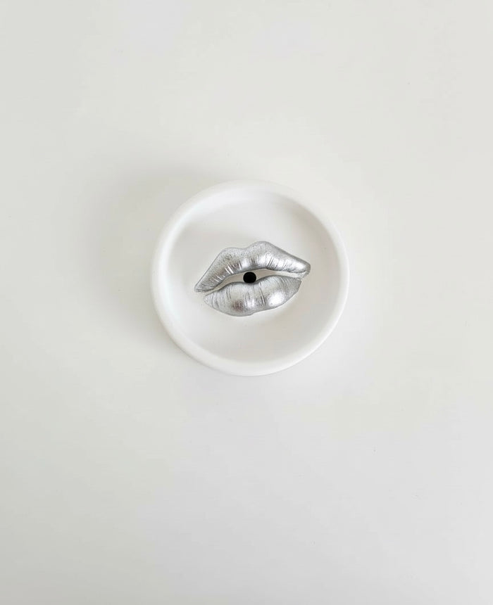 An ivory Sculptural Lips Incense Holder with silver lips, handmade by Sunni Dineen, displayed on a white surface.