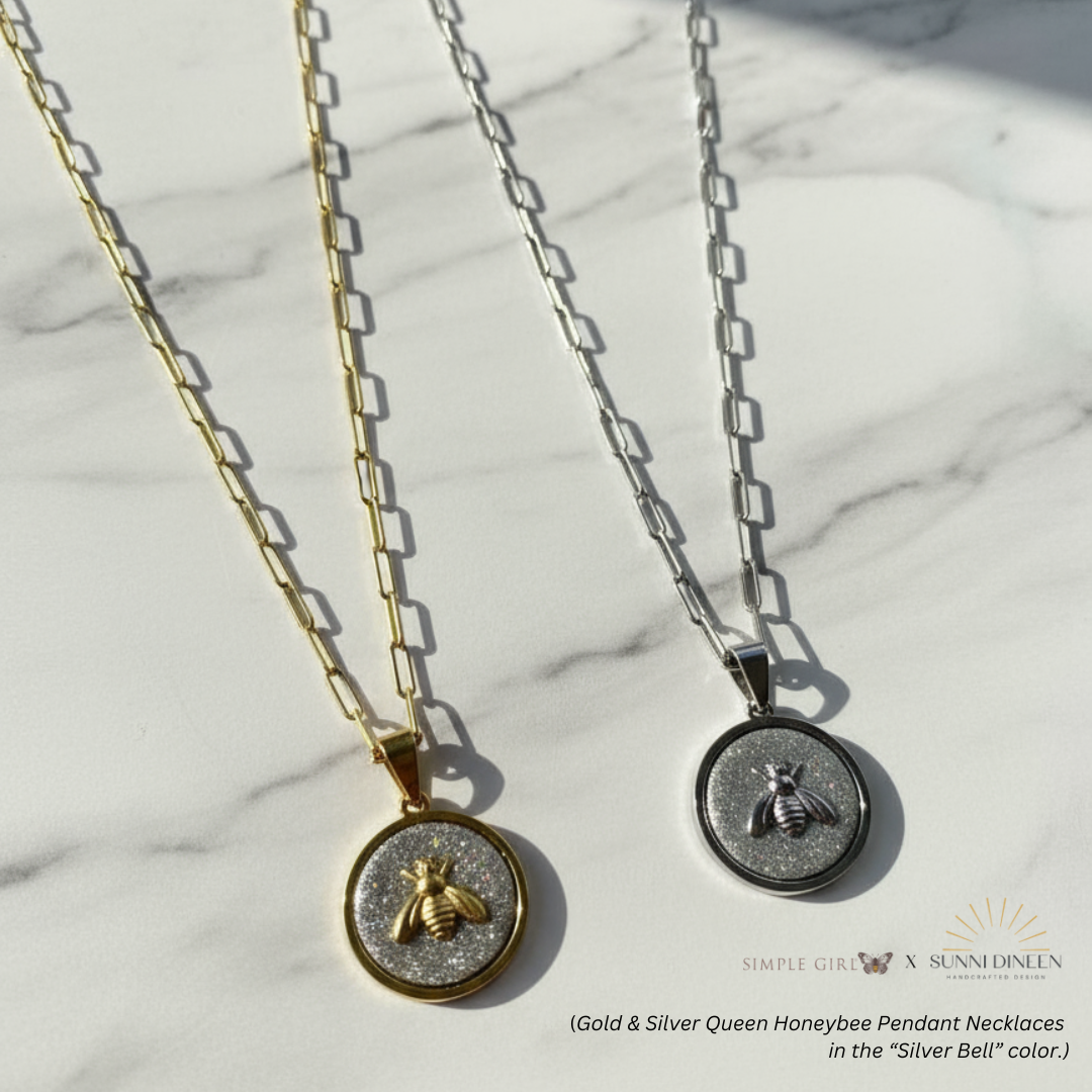 Gold and silver Queen Honeybee Pendant Necklaces in "Silver Bell" color option displayed on a marble surface.