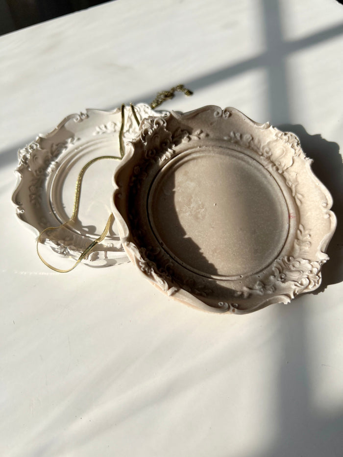 Two vintage-inspired trinket dishes in ivory and taupe tones with ornate baroque edges — handmade décor by Sunni Dineen.